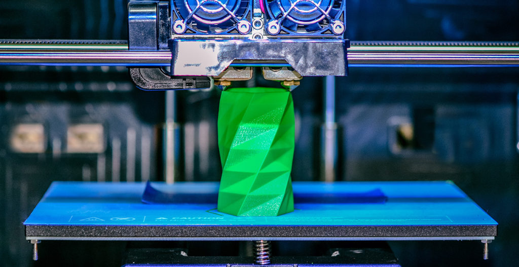3D printer works and creates an object from the hot molten plastic close-up. Automatic three dimensional 3d printer performs plastic green colors modeling in laboratory